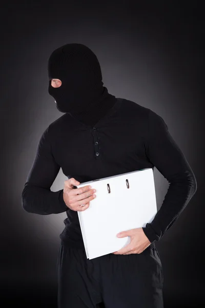 Thief in a balaclava stealing a file — Stock Photo, Image