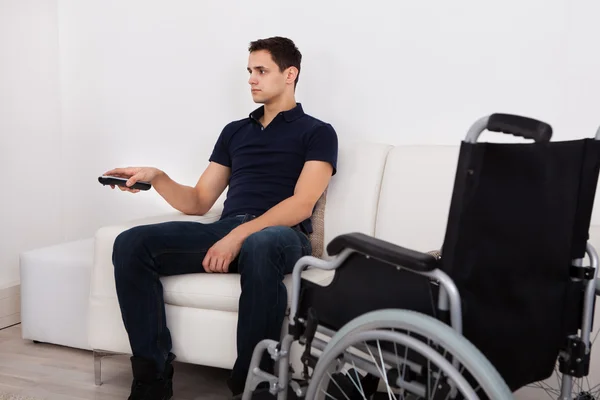 Handicap man met afstandsbediening tijdens het kijken naar televisie — Stockfoto