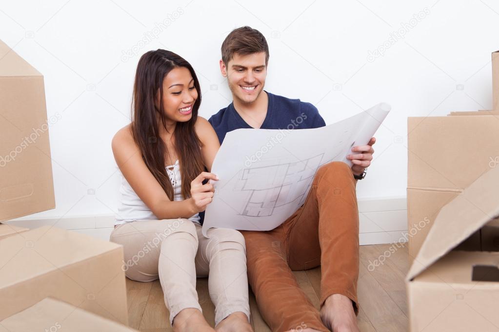 Couple Looking At Blueprint In New Home