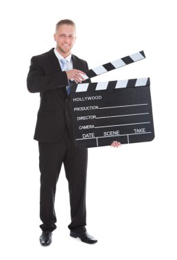 Businessman holding a blank clapper board with the arm clipart