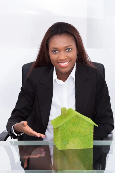 Empresária mostrando verde colorido casa na mesa — Fotografia de Stock