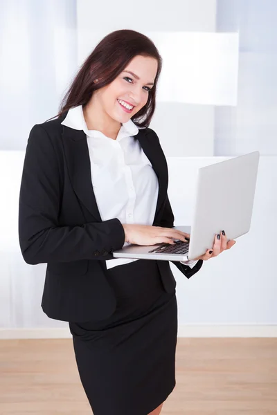 Välklädda affärskvinna med laptop i office — Stockfoto