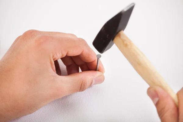 Hände hämmern weiße Wand mit Nagel — Stockfoto