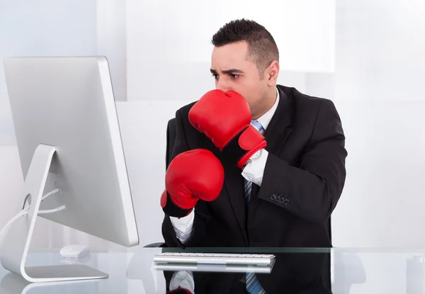 Imprenditore spaventato con guanti da boxe guardando il computer — Foto Stock