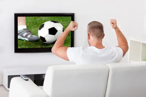 Torcedor de futebol animado assistindo um jogo na televisão — Fotografia de Stock