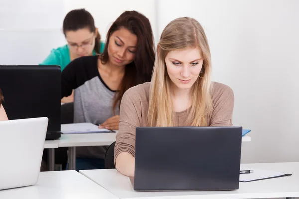 Mooie universiteitsstudent met laptop aan balie — Stockfoto