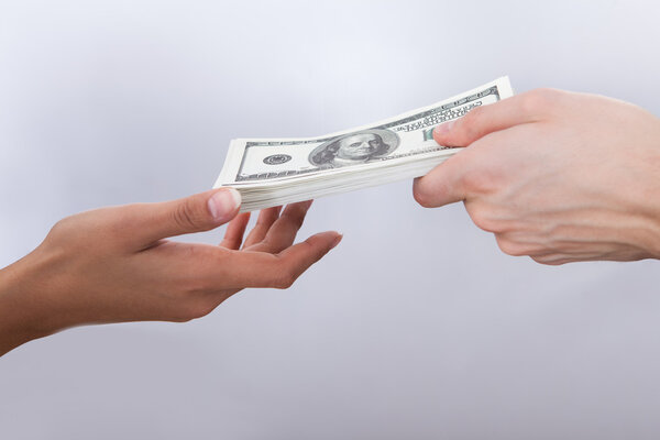 Бизнесмен дает долларовые счета коллеге
