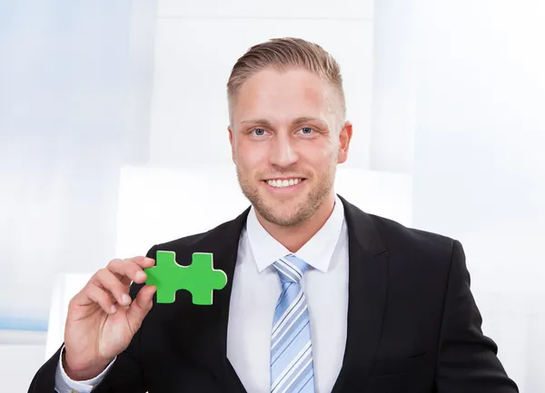 Successful businessman holding a puzzle piece — Stock Photo, Image