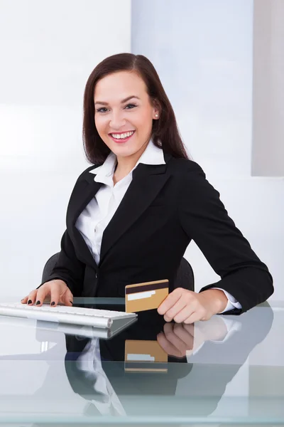 Happy Businesswoman tiene tarjeta de crédito en el escritorio — Foto de Stock