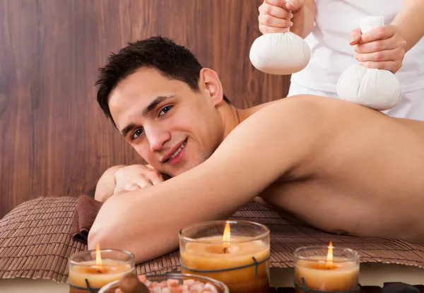 Hombre recibiendo masaje con sellos en spa —  Fotos de Stock