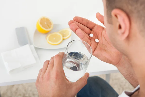 Hombre enfermo tomando tabletas con vaso de agua — Foto de Stock