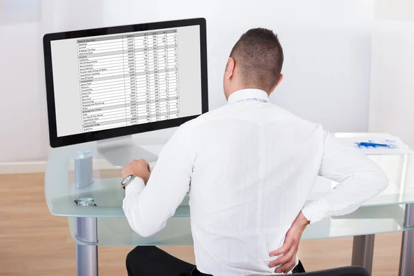 Zakenman met rugpijn met behulp van computer aan balie — Stockfoto