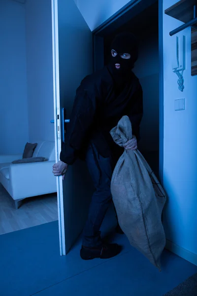 Ladrão levando saco enquanto sai da casa — Fotografia de Stock