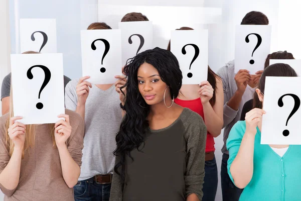 Student Surrounded By Classmates Holding Question Mark Signs — Stock Photo, Image