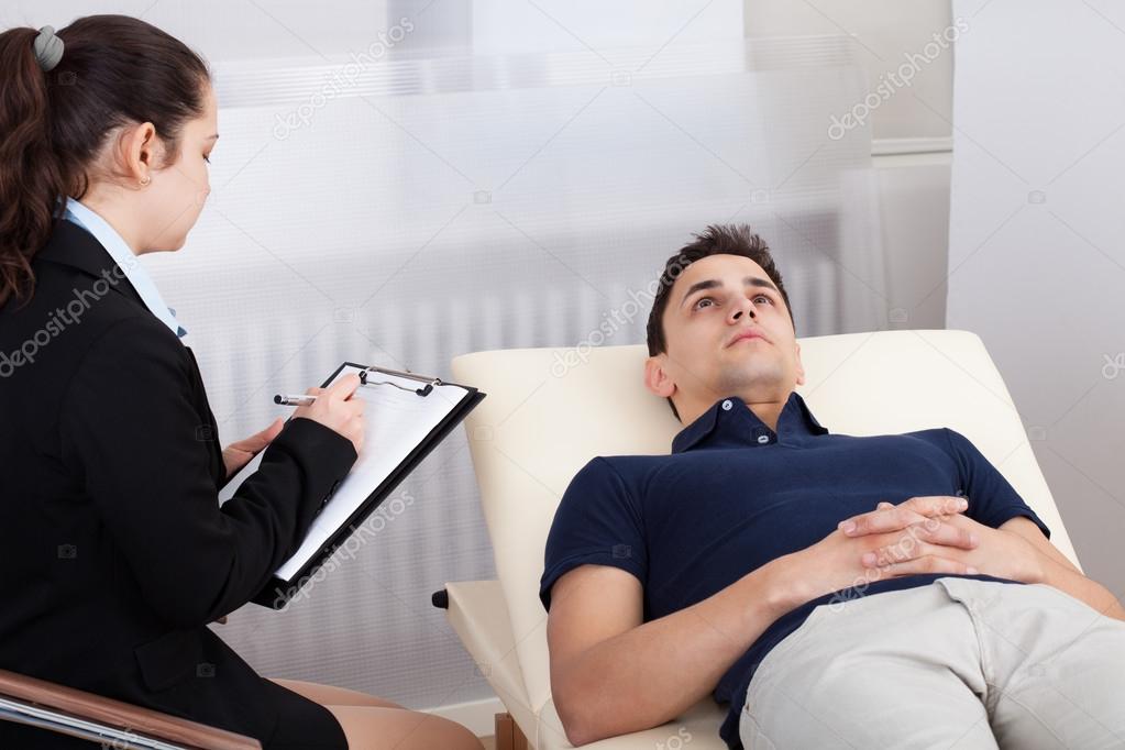 Patient Lying On Bed While Psychologist Writing Notes
