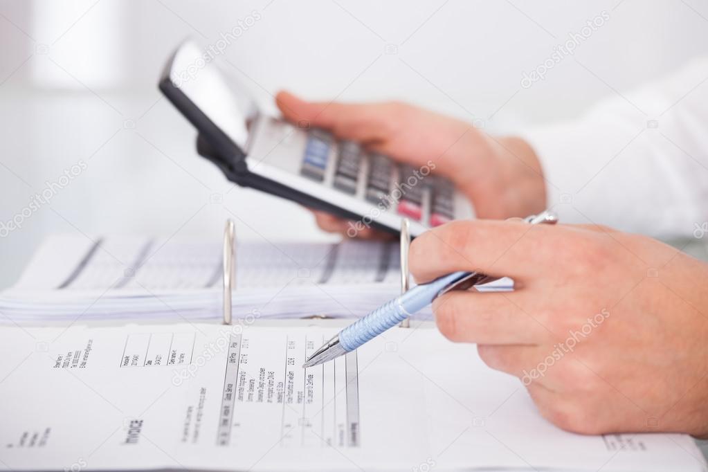 Businessman Using Calculator In Office