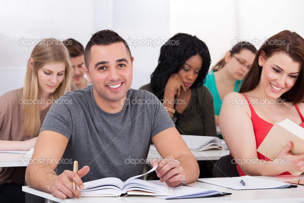 Portrait of confident male college student sitting at desk