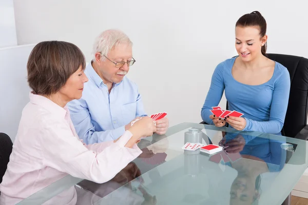 Hausmeister spielt Karten mit Senioren-Paar — Stockfoto