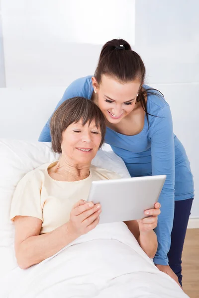 Pflegekraft und Seniorin mit digitalem Tablet — Stockfoto