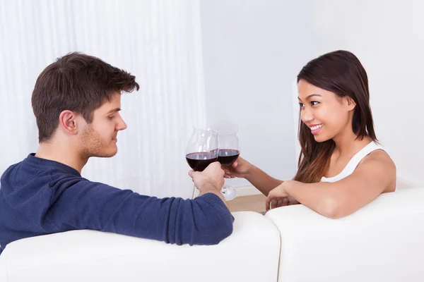 Verliefde paar roosteren wijnglazen op sofa — Stockfoto