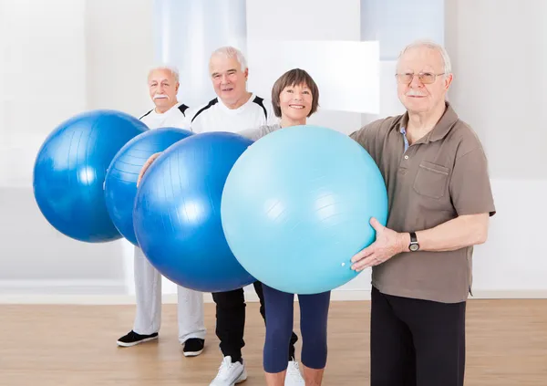Pessoas seniores confiantes carregando bolas de fitness — Fotografia de Stock