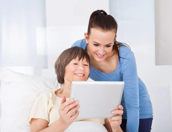 Cuidador y mujer mayor usando tableta digital — Foto de Stock