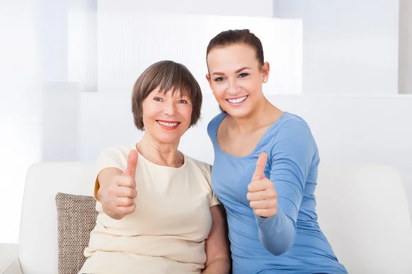 Pflegerin und Seniorin zeigen Daumen hoch — Stockfoto