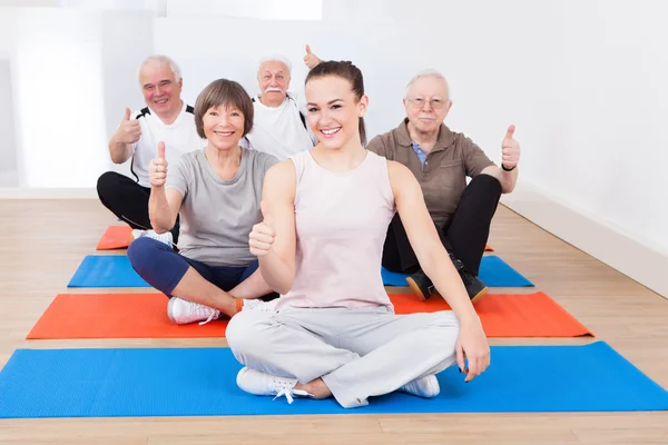 Spor salonunda üst düzey müşterileri ile kendine güvenen eğitmen — Stok fotoğraf