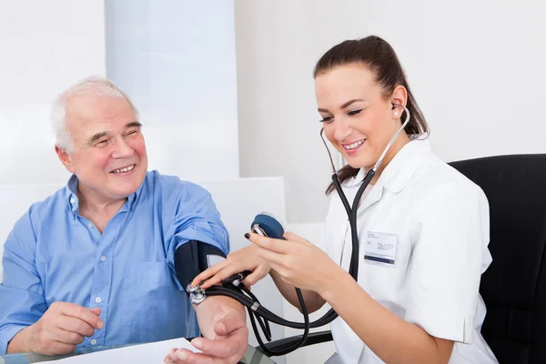 Médico midiendo la presión arterial del hombre mayor —  Fotos de Stock