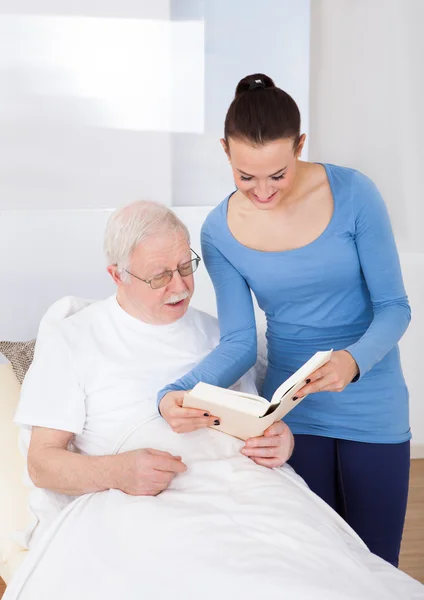 Conciërge en senior man boek lezen — Stockfoto