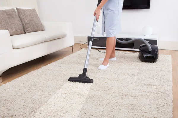 Zimmermädchen putzt Teppich mit Staubsauger — Stockfoto