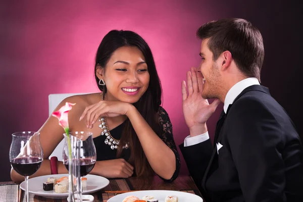 Homem sussurrando na orelha da mulher no restaurante — Fotografia de Stock