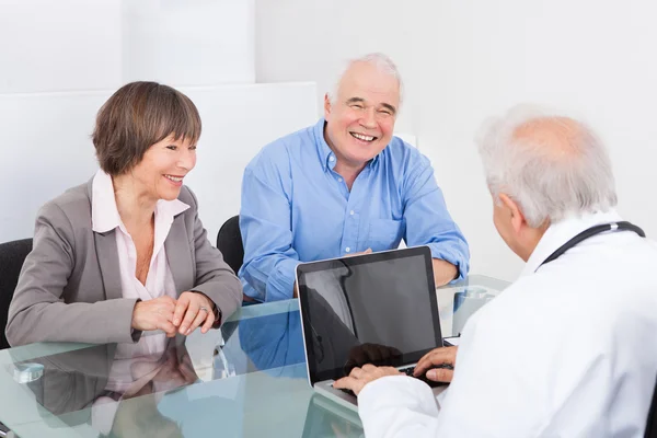 Gelukkige paar bespreken met mannelijke arts — Stockfoto