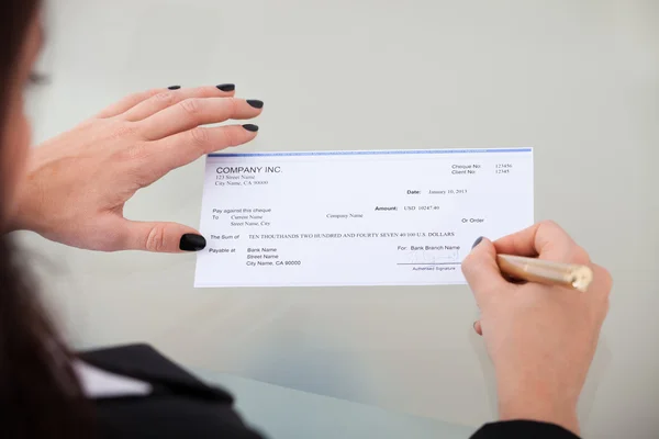 Affärskvinna undertecknandet check — Stockfoto