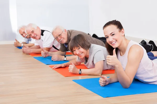 Entrenador y clientes mayores en el gimnasio — Foto de Stock