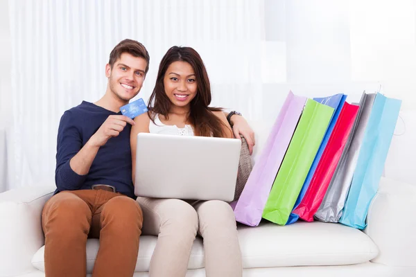 Couple Shopping en ligne avec des sacs sur le canapé — Photo