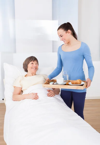 Pflegerin serviert Seniorin Frühstück — Stockfoto