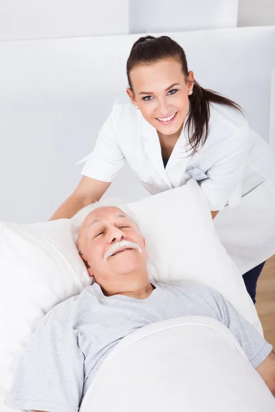 Glücklicher Arzt mit älterem Mann im Bett liegend — Stockfoto