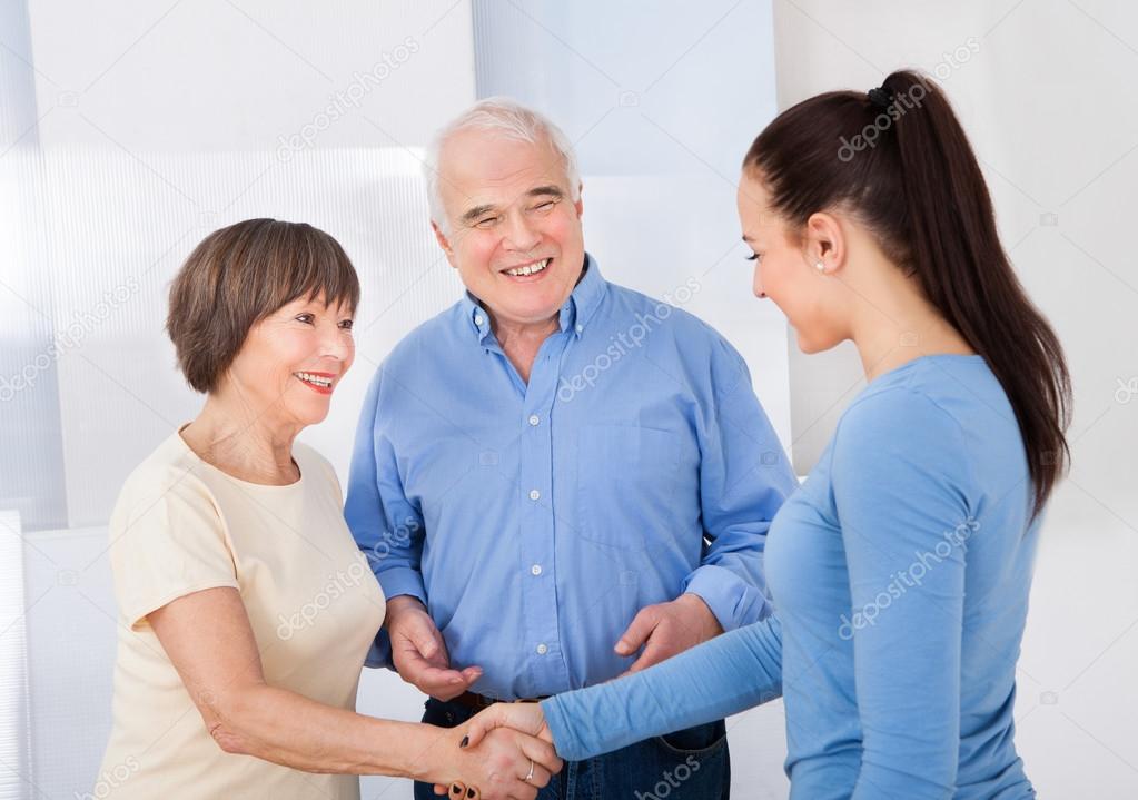 Caregiver Shaking Hands With Senior Couple