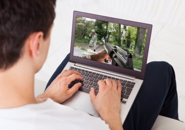 dizüstü bilgisayarınızda evde aksiyon oyunu oynayan adam