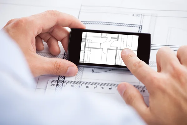 Arquiteto Analisando Blueprint On Mobilephone — Fotografia de Stock