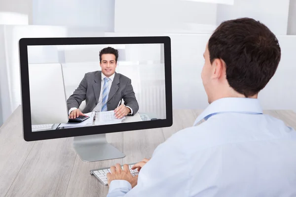 Empresario de videoconferencias con su compañero de trabajo en la PC en el escritorio — Foto de Stock