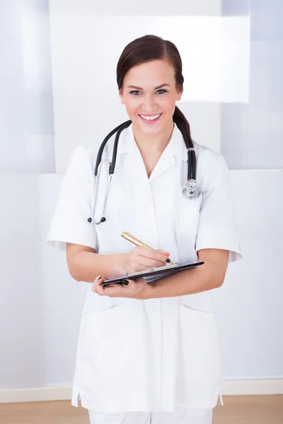 Confident Female Doctor Writing On Clipboard — Stock Photo, Image