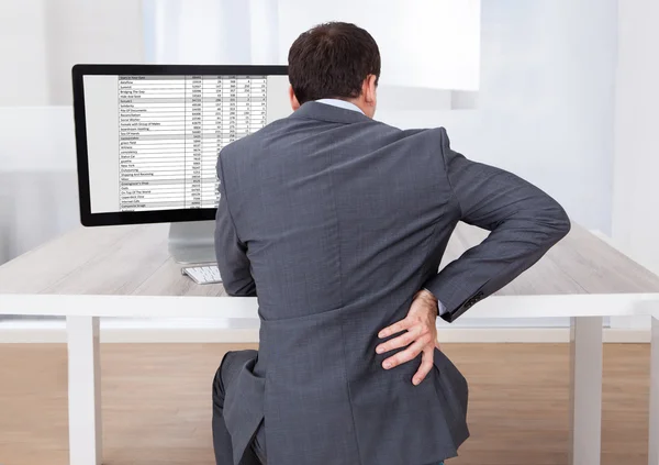 Zakenman die lijden aan rugpijn tijdens de vergadering op het Bureau — Stockfoto