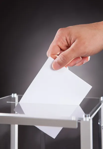 Geschäftsmann wirft Stimmzettel in Urne auf Schreibtisch — Stockfoto