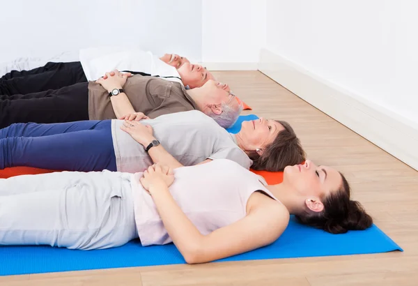 Entraîneur et personnes âgées allongés sur des tapis d'exercice — Photo