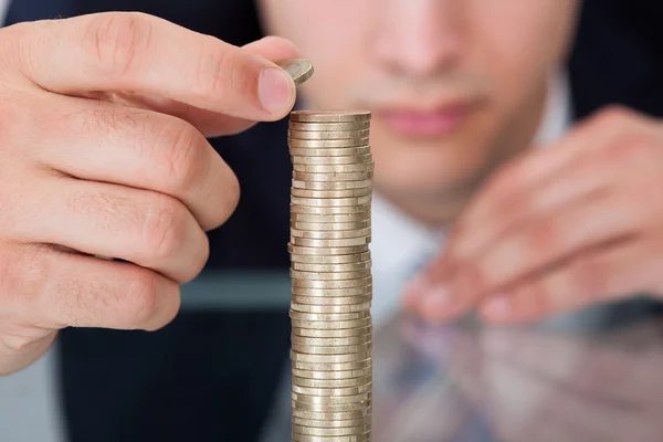 Hombre de negocios apilando monedas en el escritorio — Foto de Stock