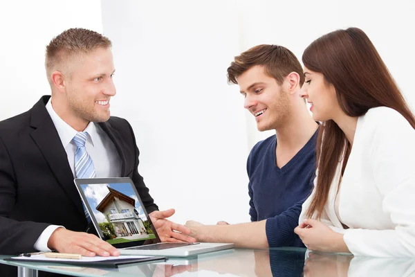 Geschäftsmann zeigt Paar Hausbild auf Laptop — Stockfoto