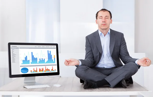 Businessman Mediating By Computer On Desk