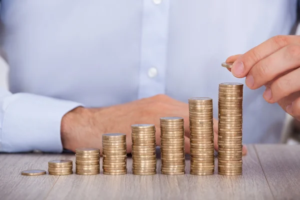 Geschäftsmann stapelt Euromünzen am Schreibtisch — Stockfoto